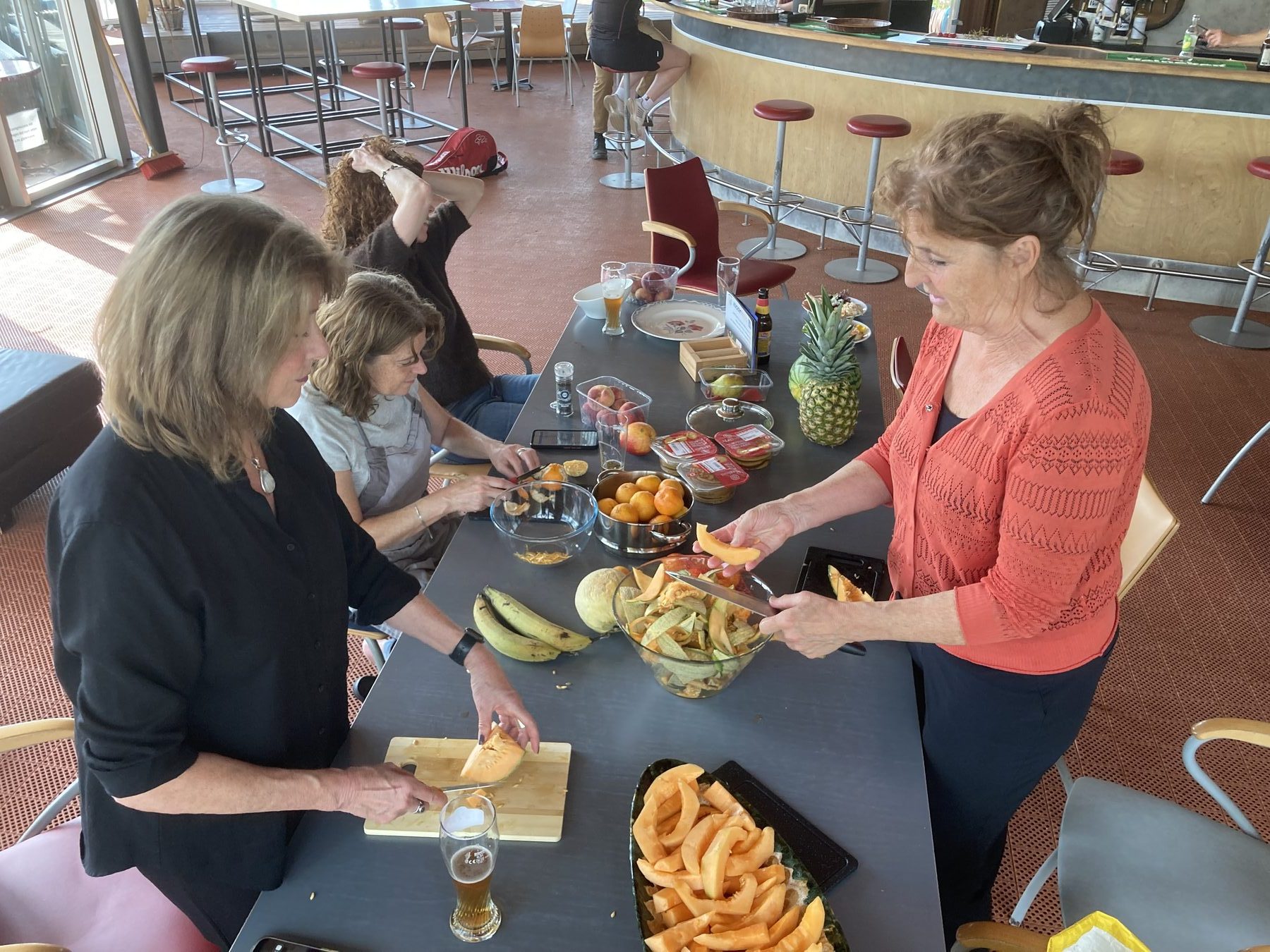 Deelnemers snijden meloen en fruit aan een tafel
